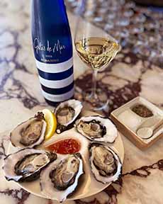 A Bottle Of Albarino Wine With Oysters On The Half Shell