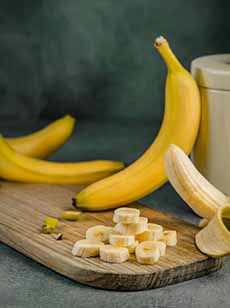 A Cutting Board With Bananas, Whole & Sliced