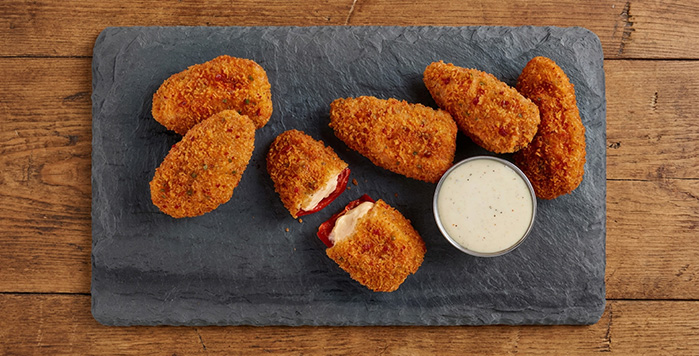 A plate of red jalapeno poppers with ranch dip.
