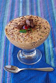 A bowl of butterscotch pudding topped with chocolate flecks.