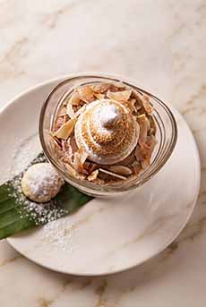 A dish of butterscotch pudding with sliced almonds and meringue.