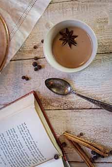 A cup of masala chai and an open book.