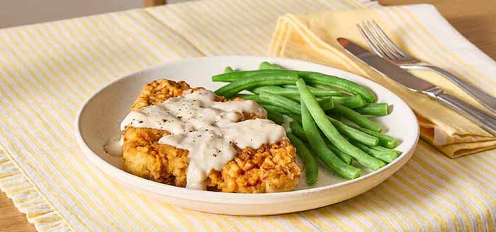 A plate of chicken fried steak and green beans.