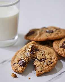 A plate of chocolate chip cookies with a glass of milk.