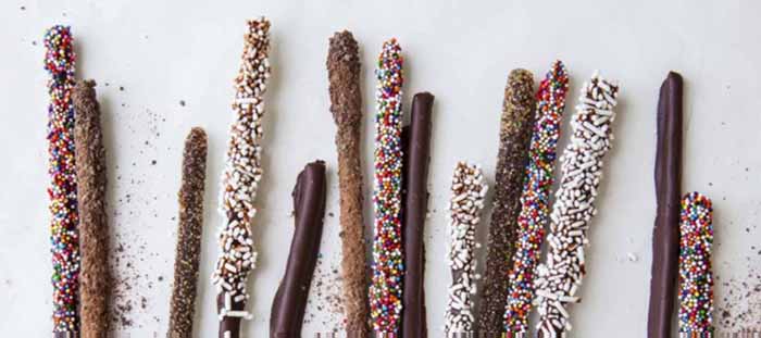 A tray of chocolate-covered breadsticks decorated with sprinkles.