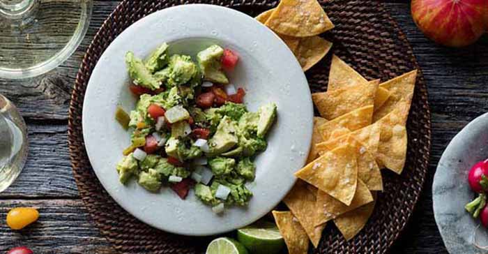 A bowl of guacamole with tortilla chips.