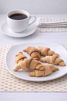 A Plate Of Cinnamon Crescents With A Cup Of Coffee