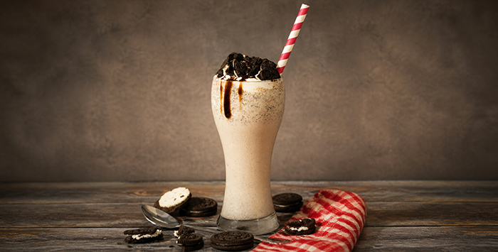 A coffee milkshake topped with Oreo cookie pieces.