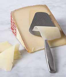 A wedge of Comte cheese and a cheese slicer.