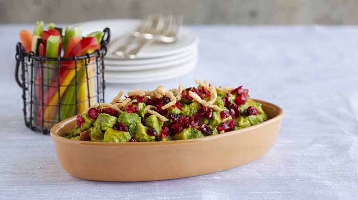 A dish of guacamole garnished with dried cranberries for the holidays.