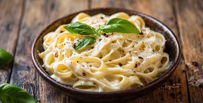 A plate of Fettuccine Alfredo on a wood tabletop.