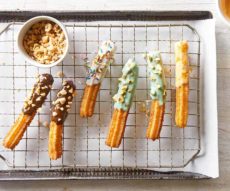 Churros dipped in royal icing and rolled in nuts.