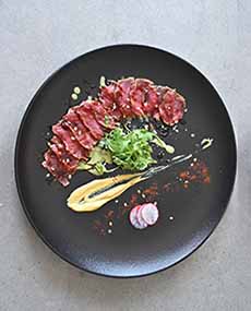 A beautifully arranged plate of beef carpaccio
