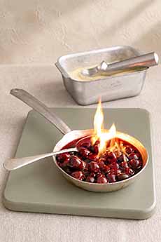 Flaming pan of cherries jubilee on a trivet.