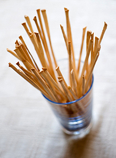 A Glass Holding Thin Breadsticks - Grissini