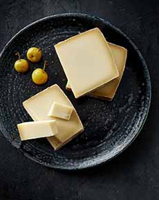 A plate of thick slices of Gruyere cheese and green olives