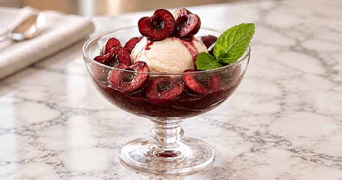 Cherries Jubilee in a stemmed glass dish using halved cherries instead of whole.