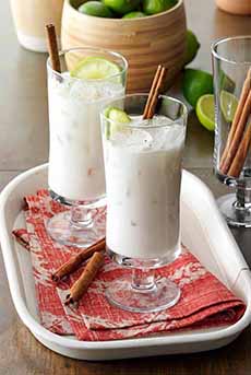 Two glasses of horchata with cinnamon stick and lime wheel garnishes