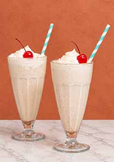 Two tall horchata milkshakes with straws.