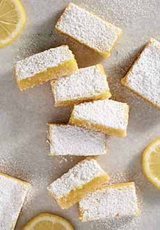 Eight lemon bars topped with powdered sugar.