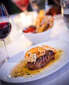 A glass of red wine with a Surf & Turf dinner.