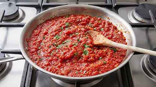 Marinara sauce cooking in a pan on the stovetop.