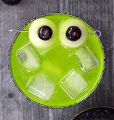 Halloween cocktail with honeydew and blueberry eyeballs.