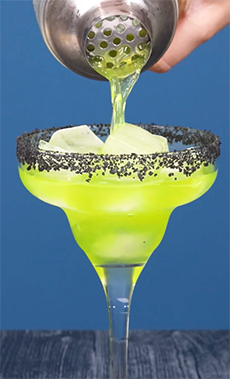 Green Halloween Margarita with black salt rim and honeydew eyeballs.