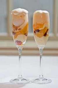 A parfait of vanilla ice cream and & Mandarin orange segments served in Champagne flutes.