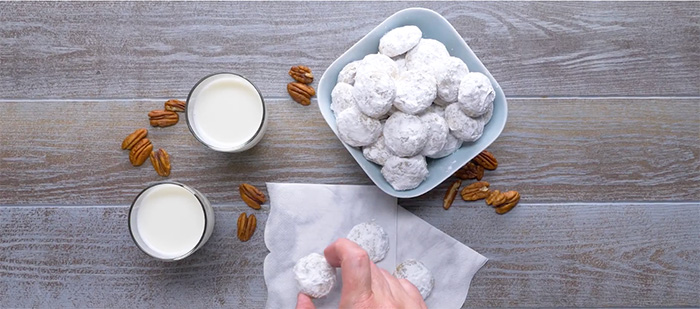 A plate of pecan sandies heavily coated with confectioners sugar.