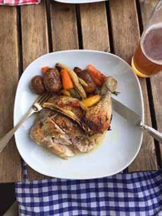 A plate of rotisserie chicken, root vegetables, and a beer.