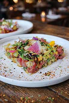 A dish of poke tartare, plated in a square.