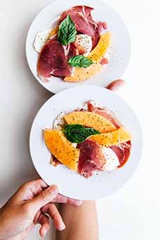 Plates of prosciutto, melon, and burrata cheese