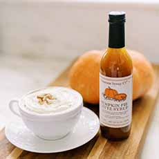 A cup of Pumpkin Spice Latte with a bottle of Sonoma Syrup.