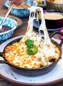 Queso Dip in a skillet with garnishes of jalapeno and cilantro.