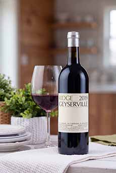 A bottle and glass of Ridge Geyserville Zinfandel on a restaurant table.
