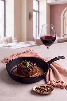 A plate of steak au poivre with a glass of red wine.