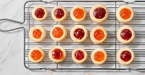 Thumbprint cookies cooling on a wire rack.