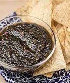 A bowl of black salsa with tortilla chips