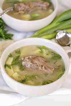 A bowl of Turkey Neck Soup with fresh herbs and chopped scallions