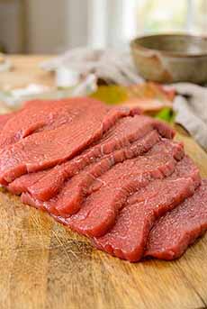 Raw veal scallops on a butcher block.