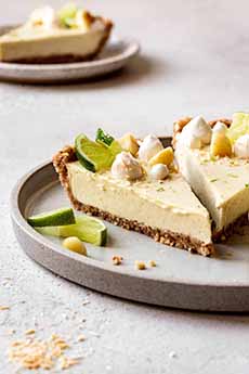 Slices of vegan Key lime pie garnished with macadamia nuts and toasted coconut.
