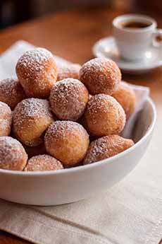 A bowl of zeppole and a cup of espresso.